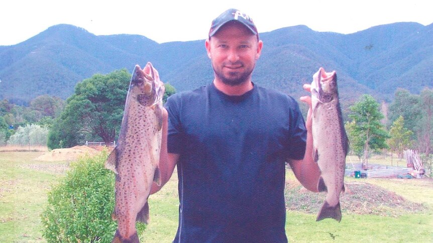 A man shows off two fish he caught.