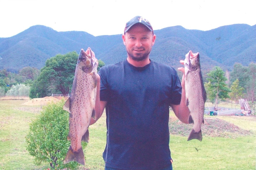 A man shows off two fish he caught.