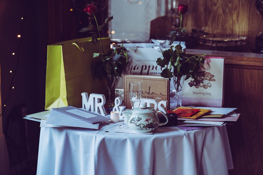 A table at a wedding, laden with gifts and cards.