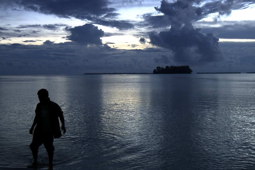 A person stands in the water at Manus Island.