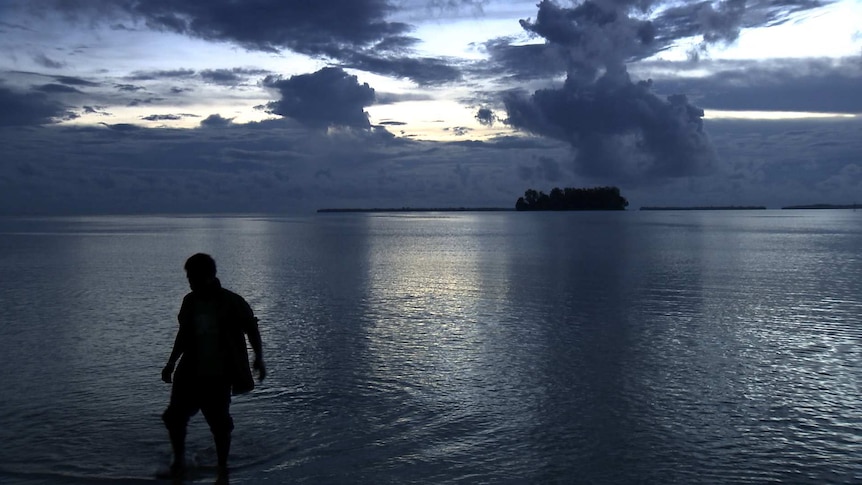 A person stands in the water at Manus Island.