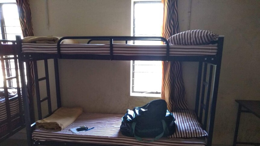 A bunk bed with red and white striped mattresses and keys and a bag sitting on the bottom bunk.