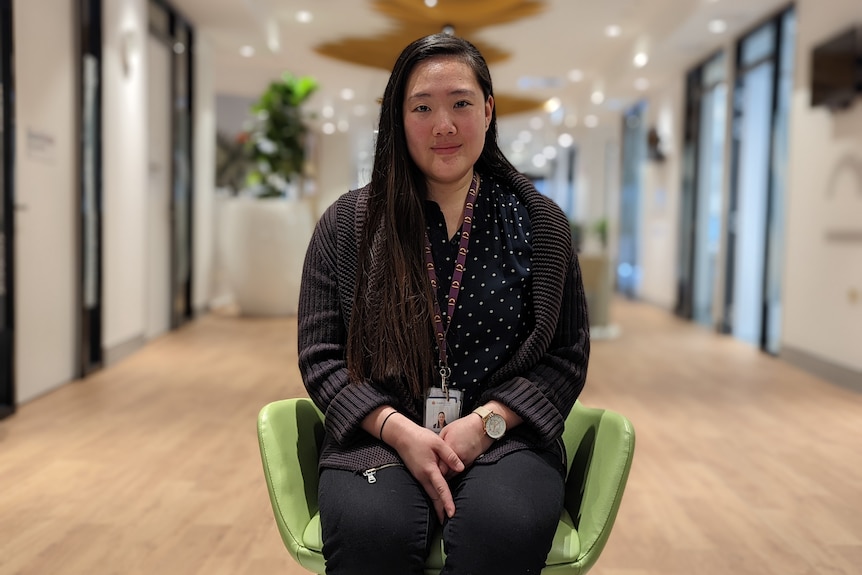 Natalie Wo sits on a green chair in the centre of the photo inside Midland Head to Health