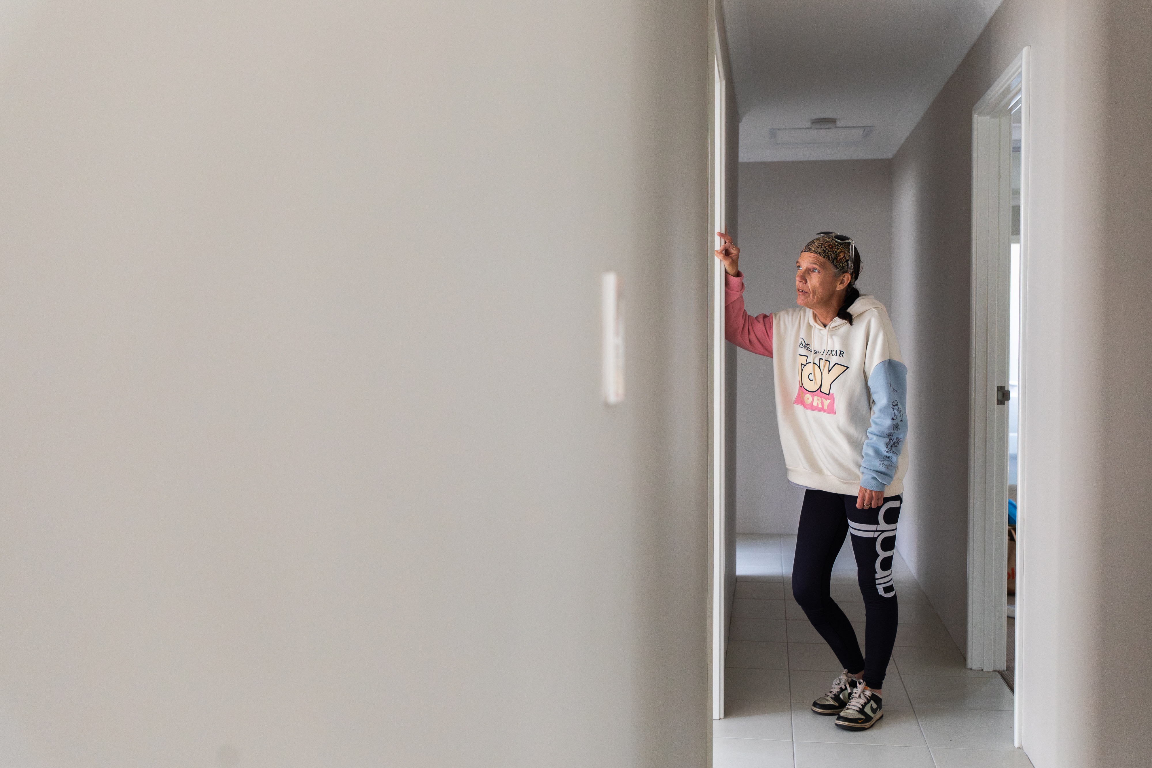 Rebecca Hendrix está parada em um corredor vazio olhando por uma porta.