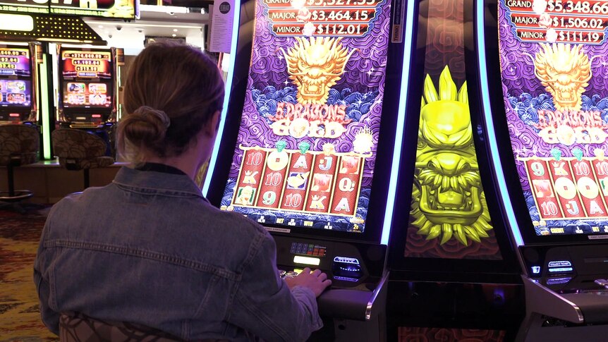 a woman sitting at a poker machine with her back to the camera