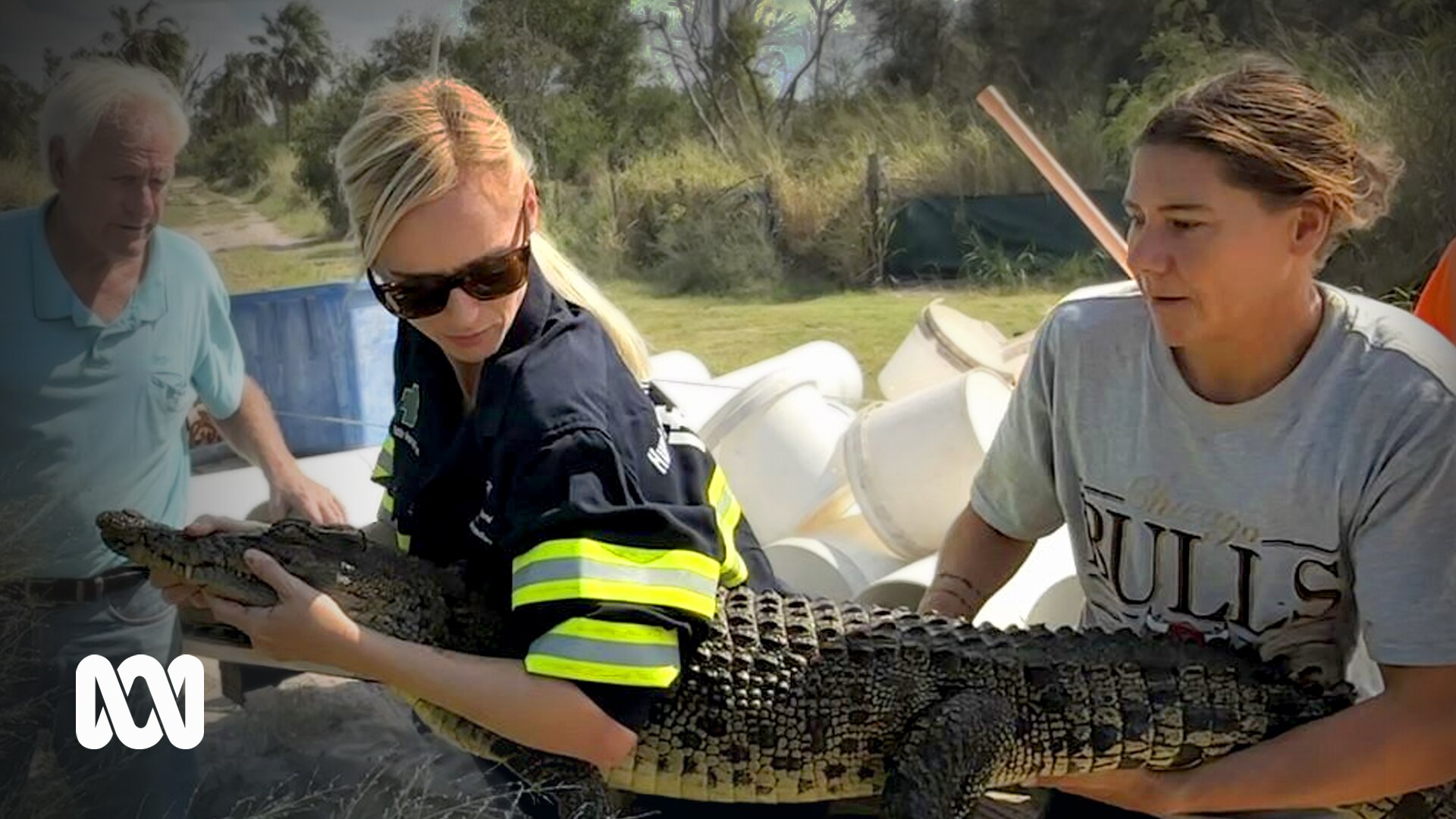 two women hold a small crocodile