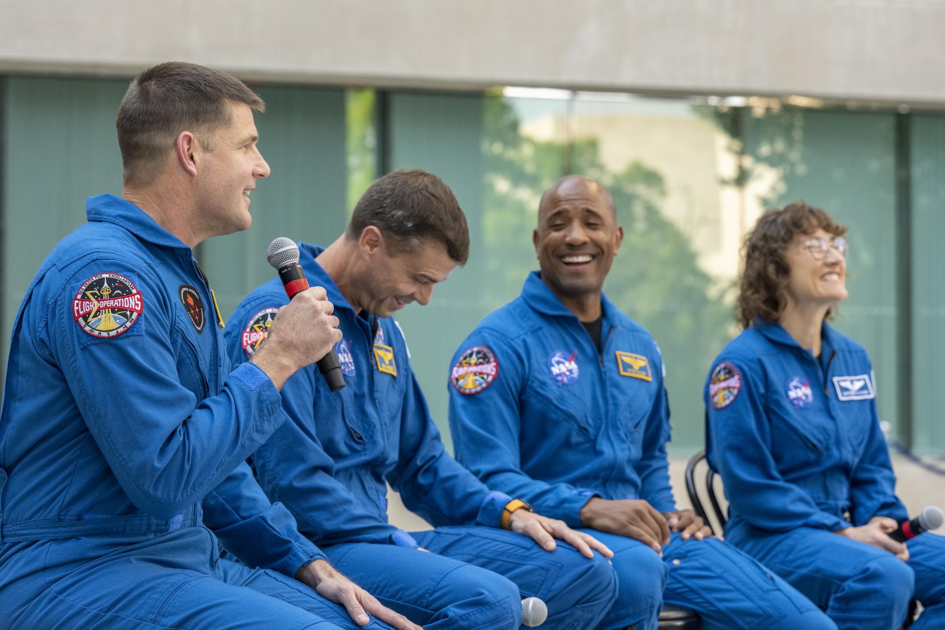 The four Artemis II astronauts sit at an event laughing. 