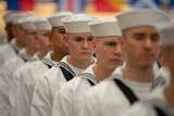 Navy Sailors dressed in white uniforms graduate from boot camp.