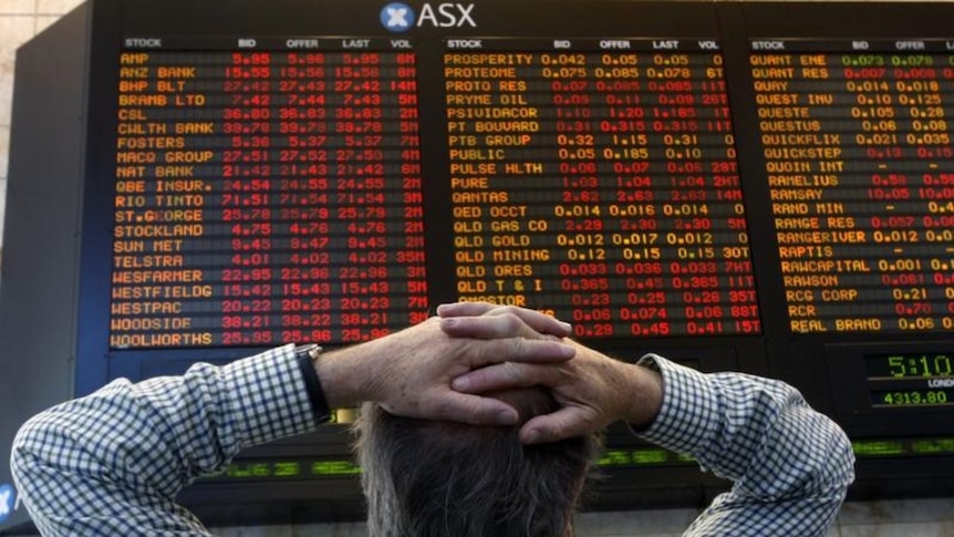 A man stands with his hands on his head looking at the ASX numbers.