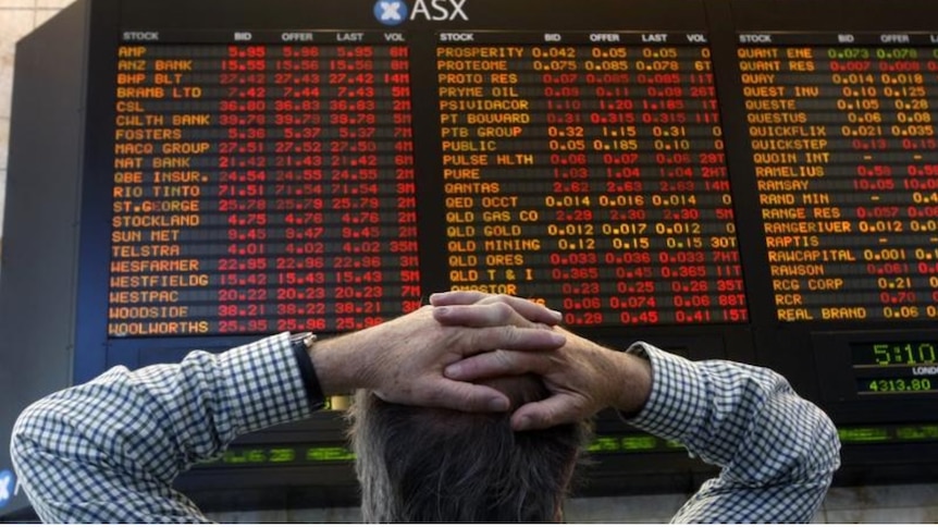 A man stands with his hands on his head looking at the ASX numbers.