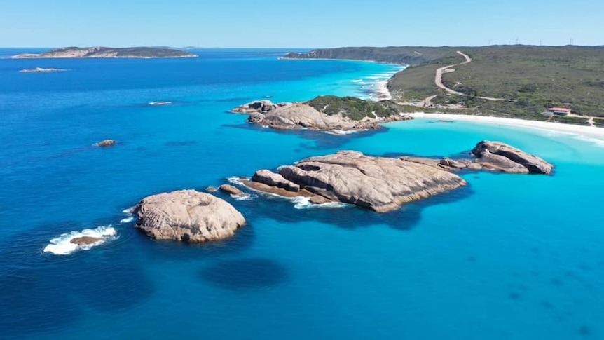 Twilight Beach is pictured by a drone, showing rocks, bright blue water, a road snaking along the coast