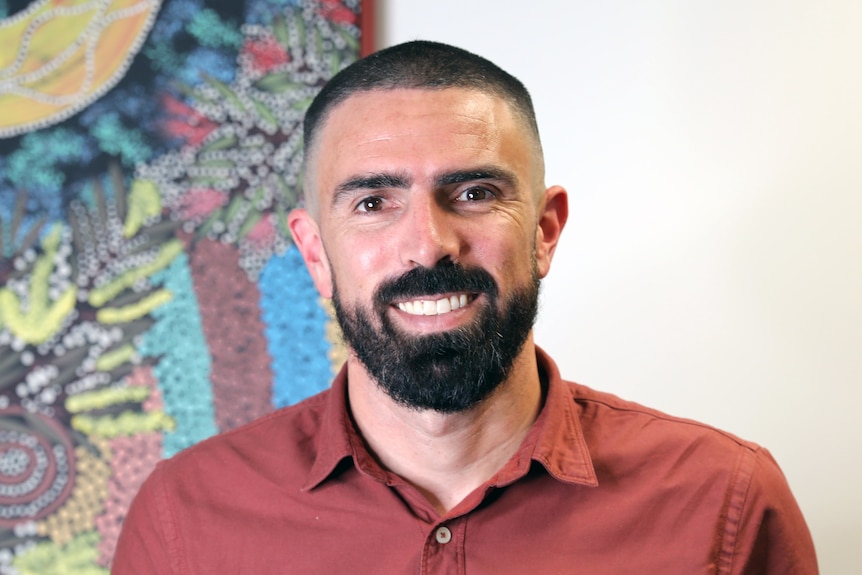 A doctor in front of Aboriginal wall art