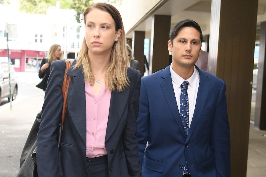 A woman and man walk down the street holding hands.