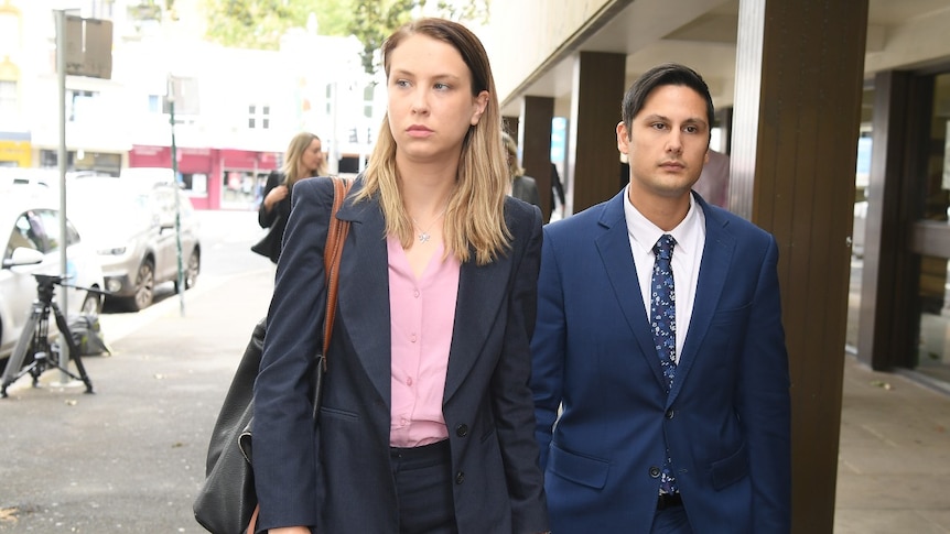 A woman and man walk down the street holding hands.