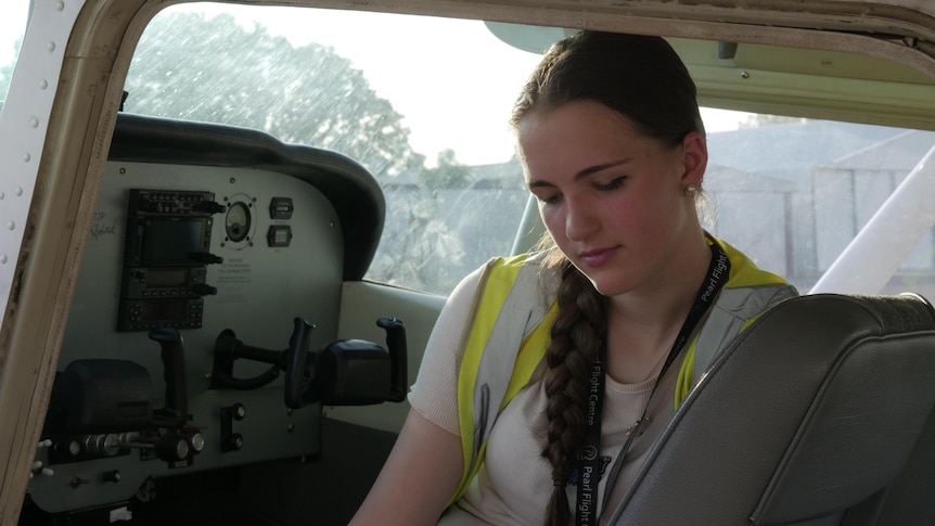 A young woman sitting behind the controls of a light aircraft. 