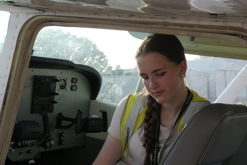 A young woman sitting behind the controls of a light aircraft. 