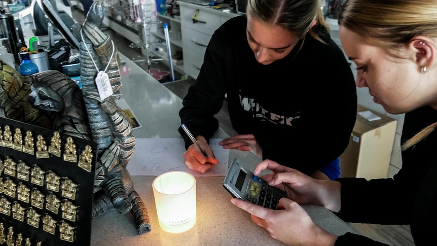 Two female workers using a calculator in a newsagency during a blackout.  