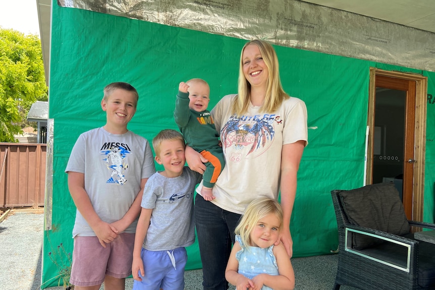 Four kids stand with their mum in their outside area