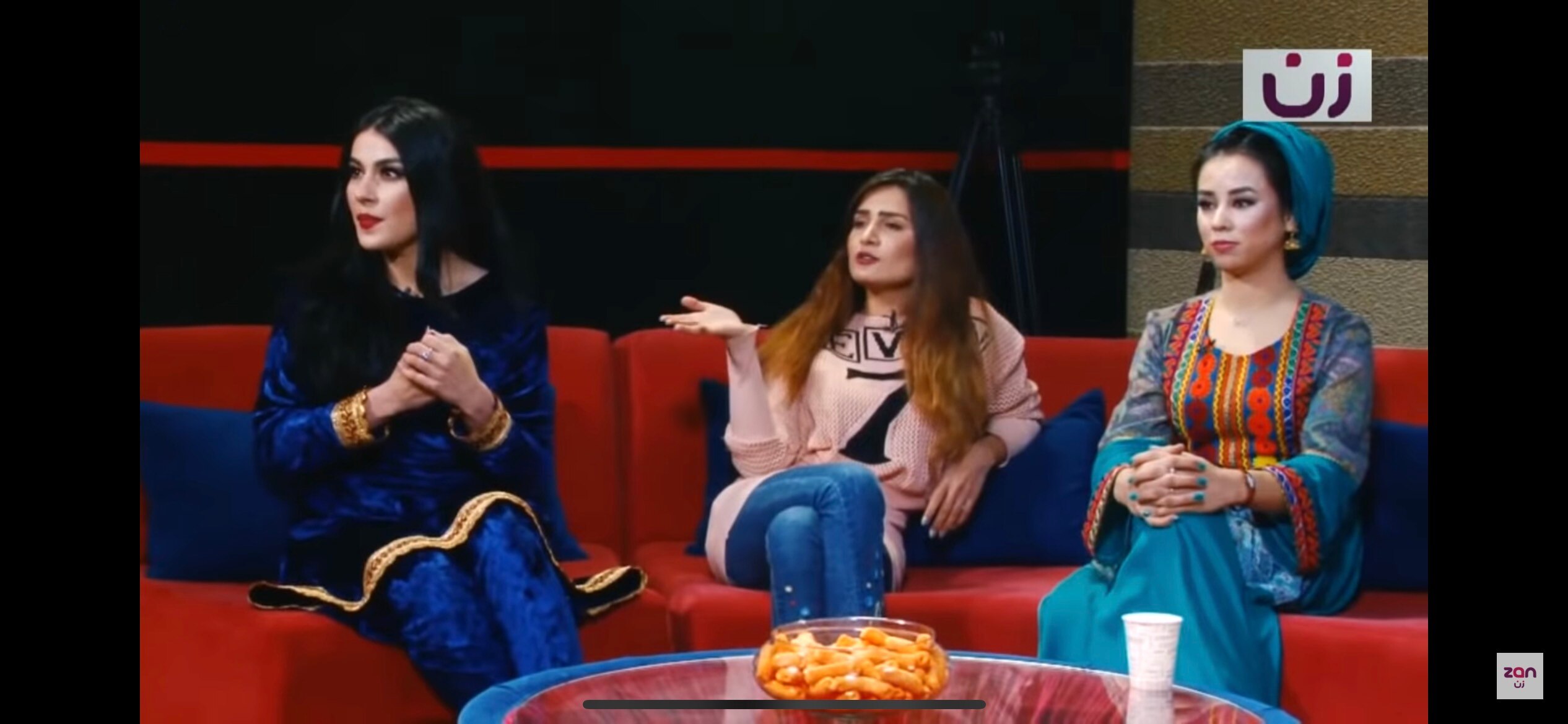 Three Afghan women sit on a couch on a tv set