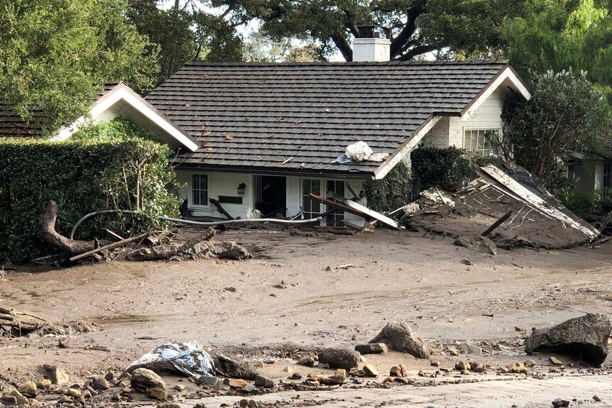 A cottages is surrounded by several feet of mud and debris