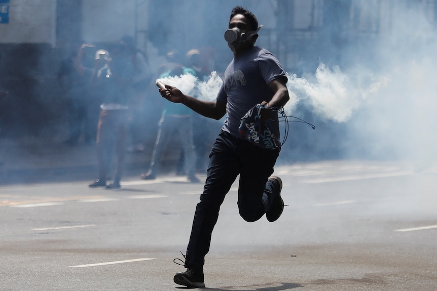 Man throws tear gas while running on street.