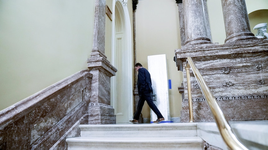US Senator Joe Manchin walks down a hall in the capitol building.