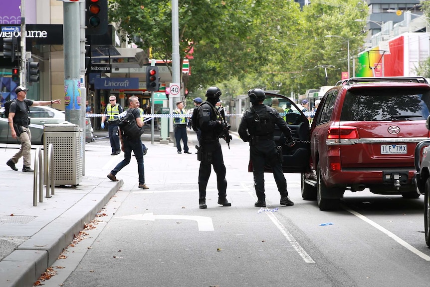 Police are seen at the corner of Elizabeth and Bourke streets