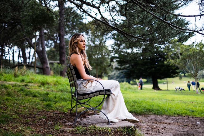 A woman sits on a park bench.