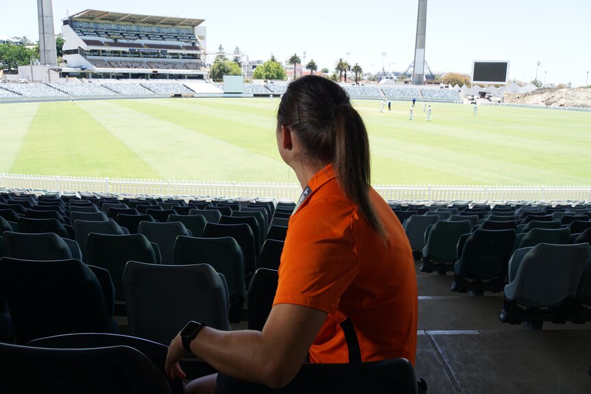 Taneale Peschel sits in the stand of the WACA Ground, watching a cricket game being played