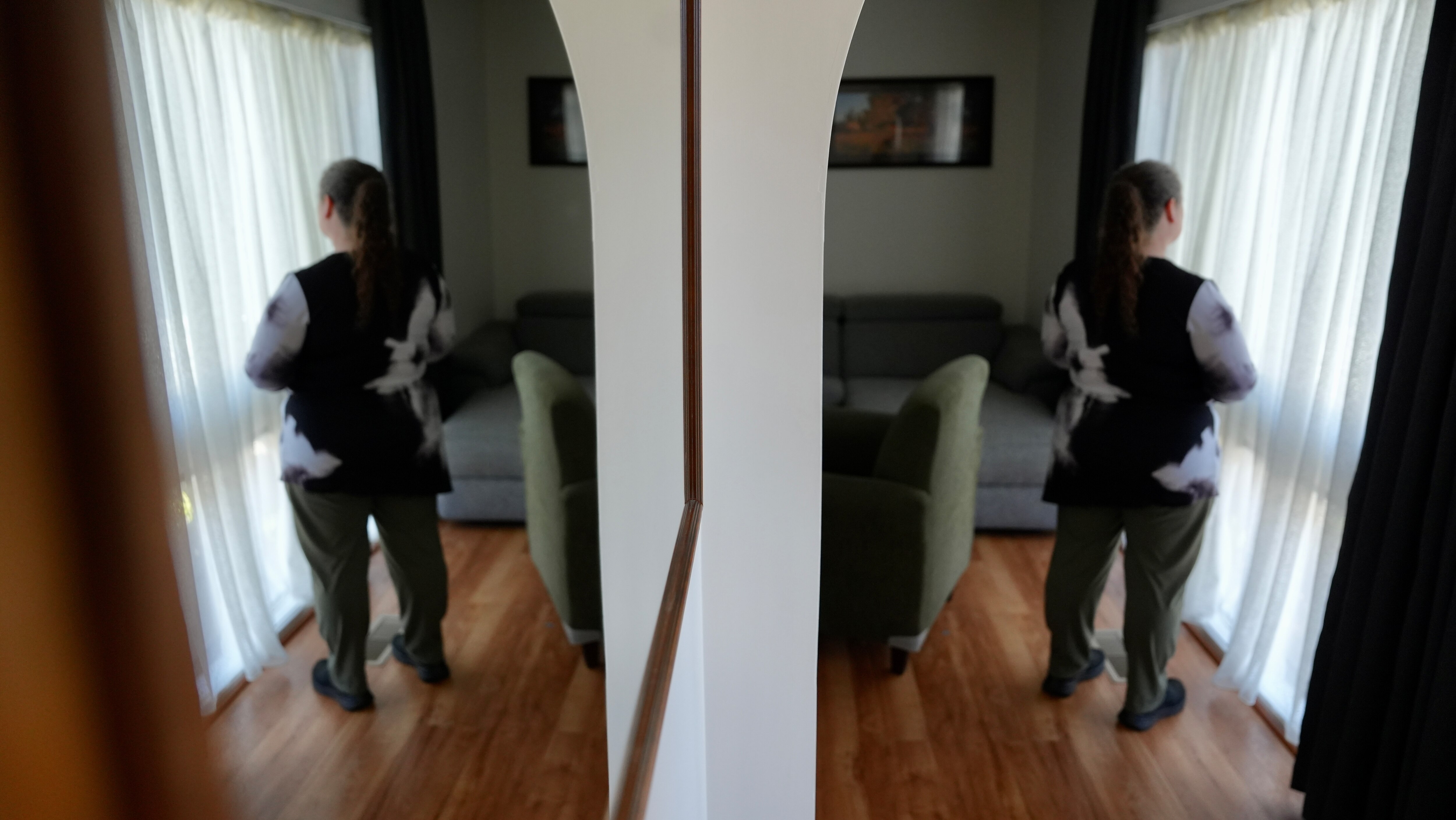 an unidentifiable woman looks out a window