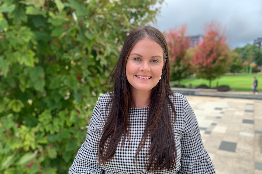 Melissa Bannister smiles at the camera with greenery in the background..