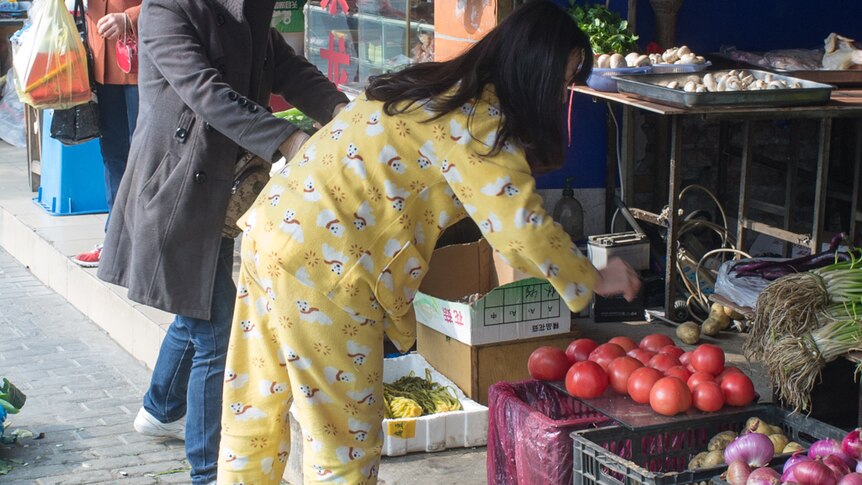A woman is seen shopping for fruits and vegetables at a Chinese market.