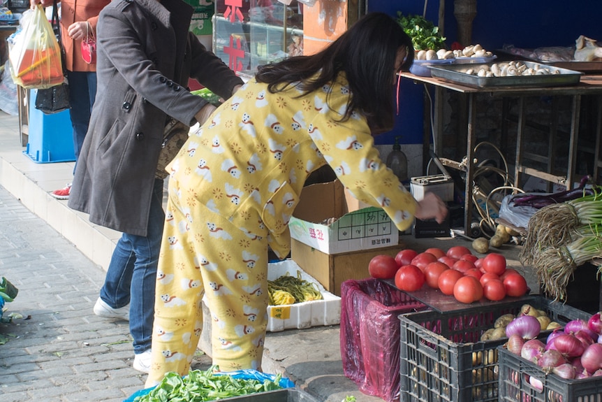 A woman is seen shopping for fruits and vegetables at a Chinese market.