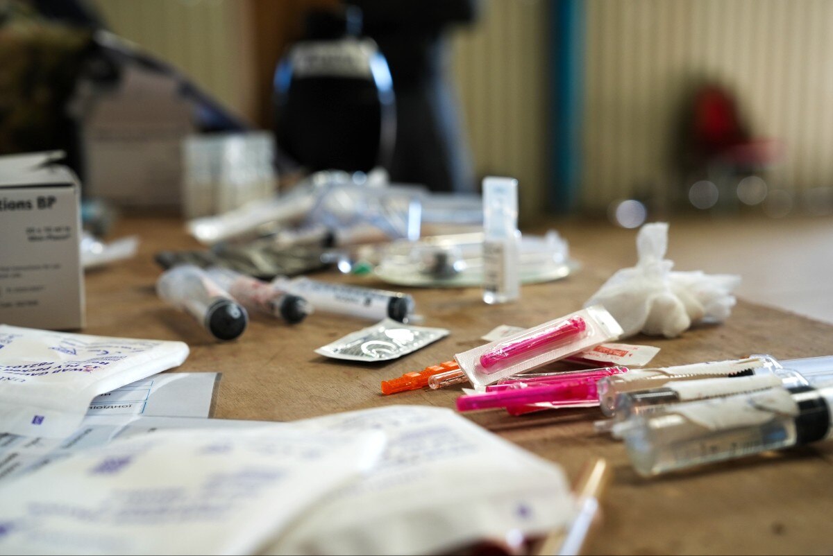 Medical paraphenalia including needles and swabs, on a table.