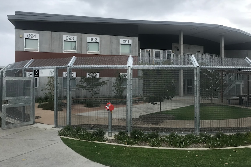 A fence and a prison block on a cloudy day.