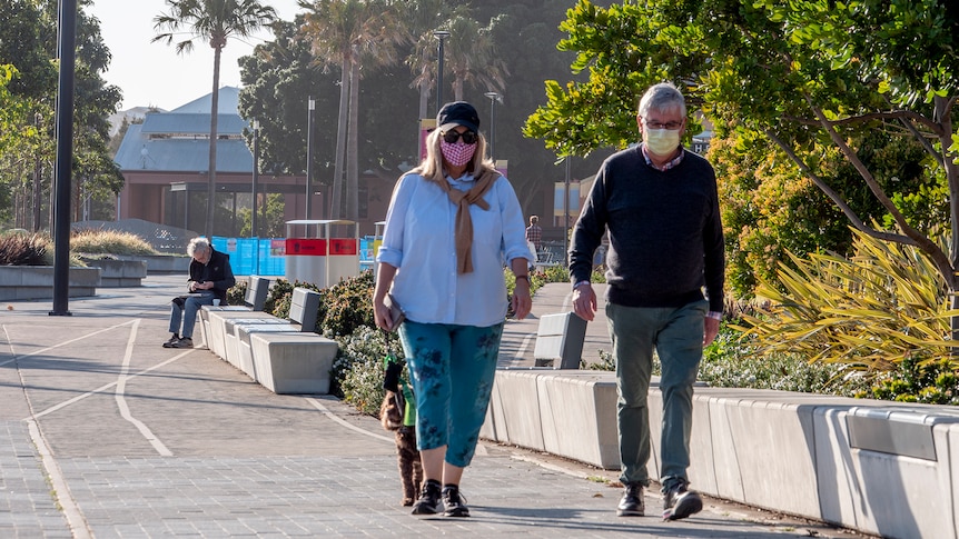 A couple with masks on walking in Newcastle