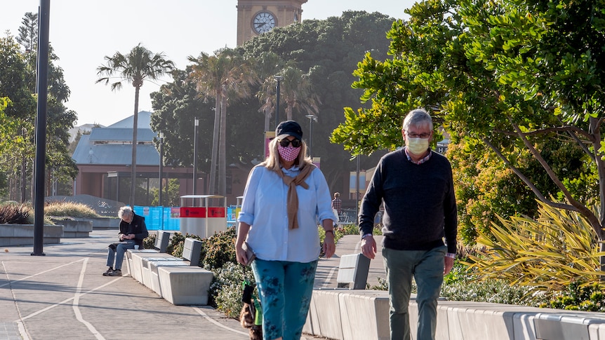 A man and a woman walking their dog along a deserted city street.