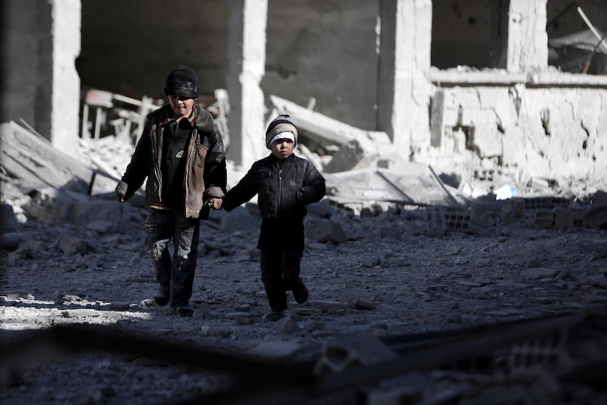 Syrian children walk through the debris of buildings destroyed in an airstrike.