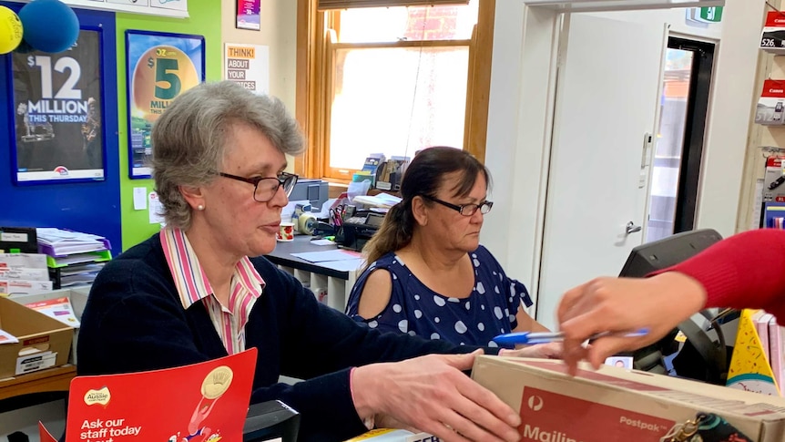 Newsagent Marg Carmody and her colleague serve customers in the Boorowa newsagent, in southern New South Wales.