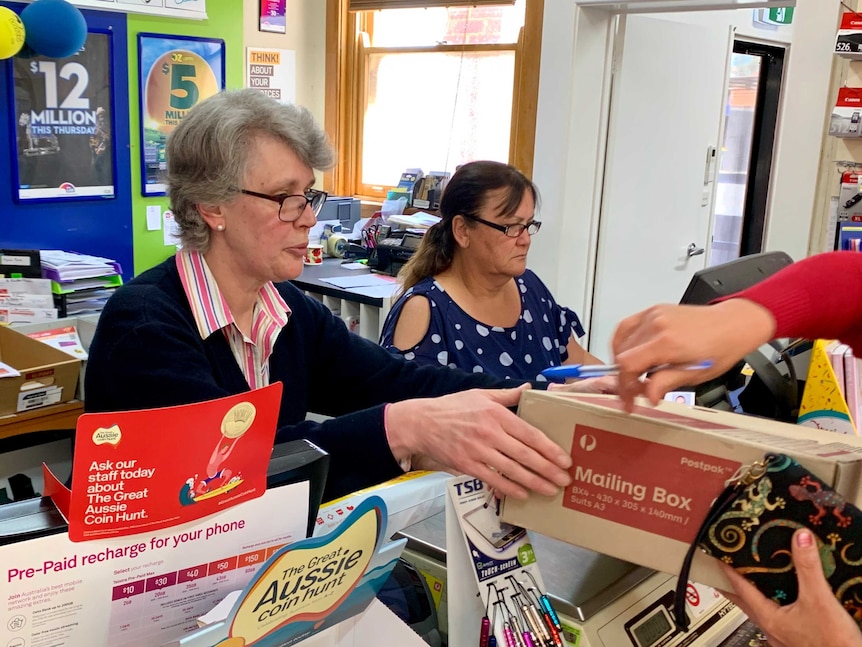 Newsagent Marg Carmody and her colleague serve customers in the Boorowa newsagent, in southern New South Wales.