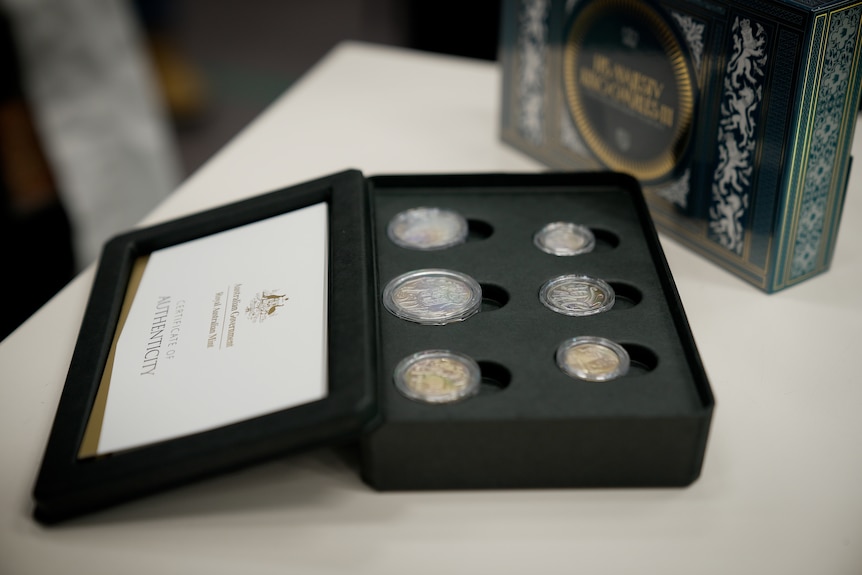 Shiny silver coins on display inside the Mint with an effigy of King Charles III on the back.