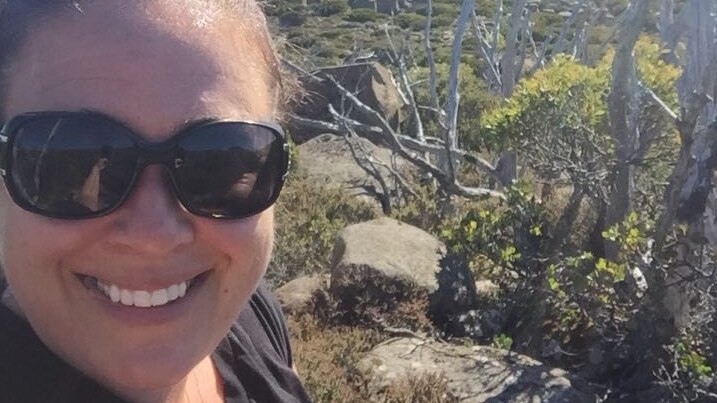 Selfie of a smiling woman wearing sunglasses in the bush.