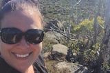 Selfie of a smiling woman wearing sunglasses in the bush.