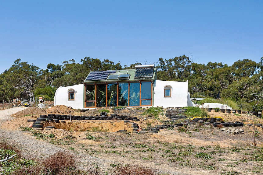 A white round house is pictured, it has a glass front and is half buried in the ground.