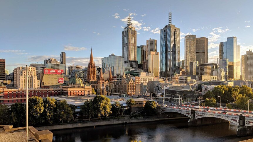 Melbourne's Yarra River in the foreground, with a view across it to Flinder's Street Station and the tall buildings of the CBD.