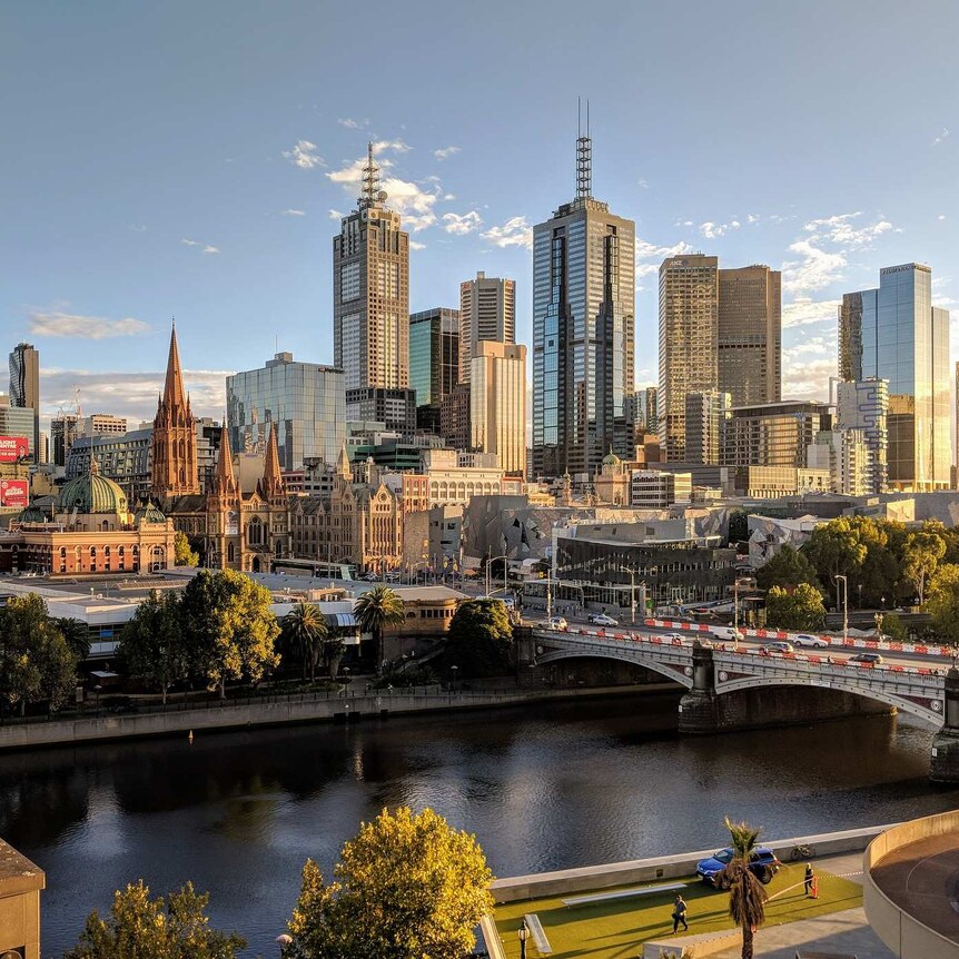Melbourne's Yarra River in the foreground, with a view across it to Flinder's Street Station and the tall buildings of the CBD.