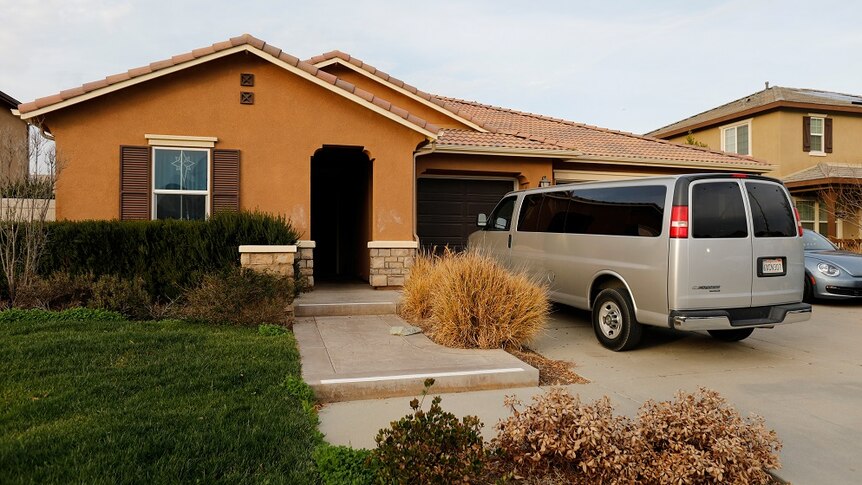 A van is parked in the driveway of a brown brick, single story house.