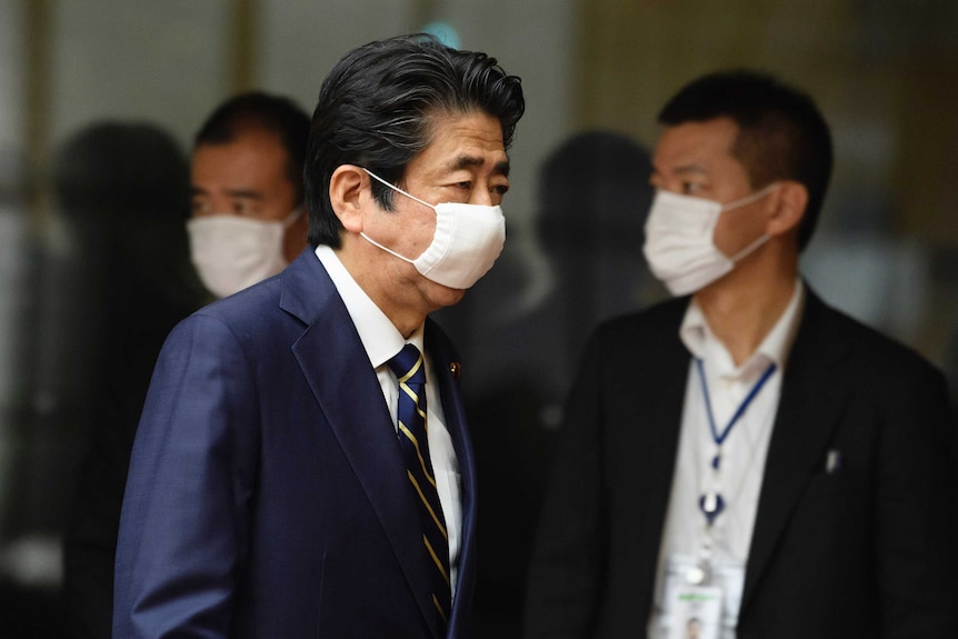 a man in a suit wears a surgical mask.