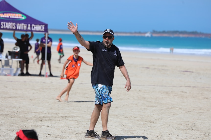 man in boardies blows whistle