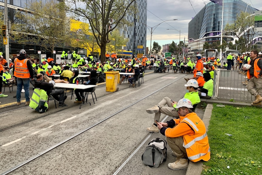 Construction workers wearing high-vis clothing blocking tram tracks.